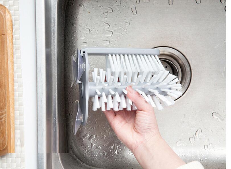 A gray suction cup brush for the kitchen, measuring approximately 17.5 by 14 centimeters. Made from PP+PVC materials, featuring a double-head design for effective cleaning