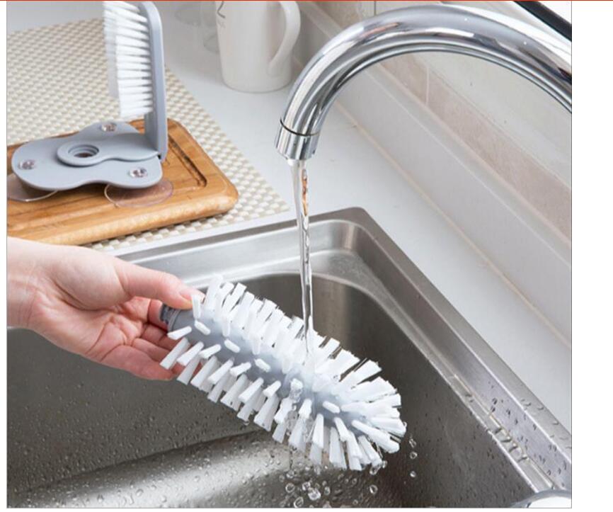 A gray suction cup brush for the kitchen, measuring approximately 17.5 by 14 centimeters. Made from PP+PVC materials, featuring a double-head design for effective cleaning