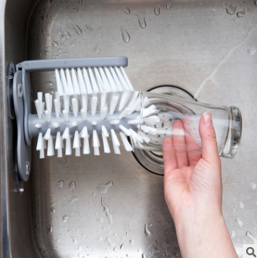 A gray suction cup brush for the kitchen, measuring approximately 17.5 by 14 centimeters. Made from PP+PVC materials, featuring a double-head design for effective cleaning